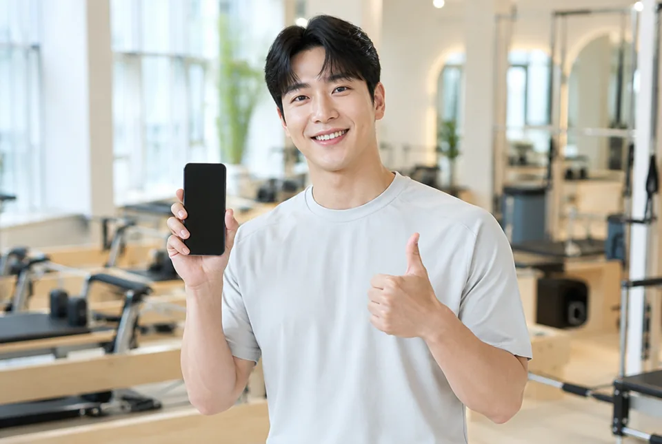 필라테스 스튜디오에서 휴대폰을 들고 웃는 사장님